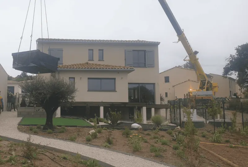 Spa bâché suspendu au crochet de la grue au-dessus de la maison, à Saint-Vincent-de-Barbeyrargues