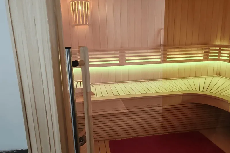 Intérieur d'un sauna finlandais en bois clair, banquettes éclairées, à Thézan-lès-Béziers