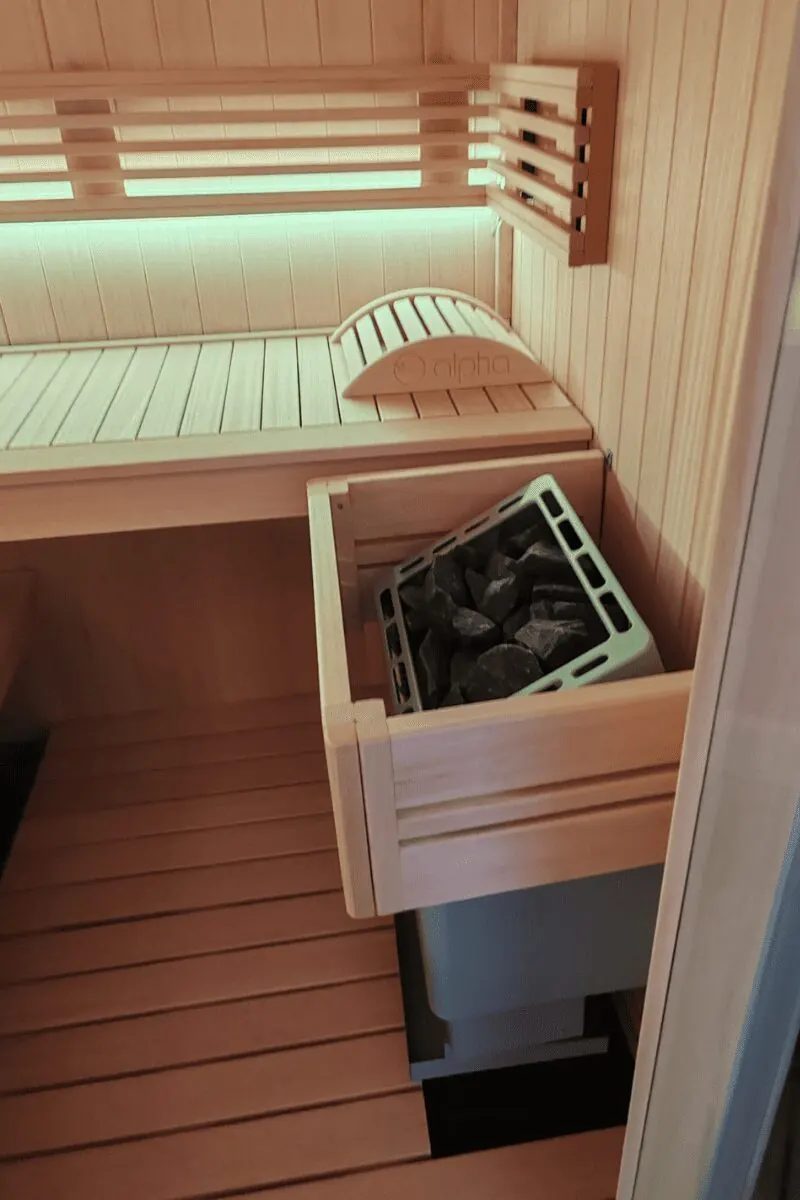 Poêle à pierres d'un sauna finlandais sous la banquette